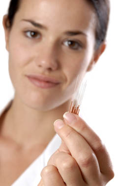 Woman holding copper handled needles. 